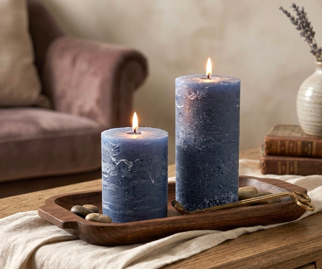 Two navy blue rustic surface candles on a wooden tray with a blurred background