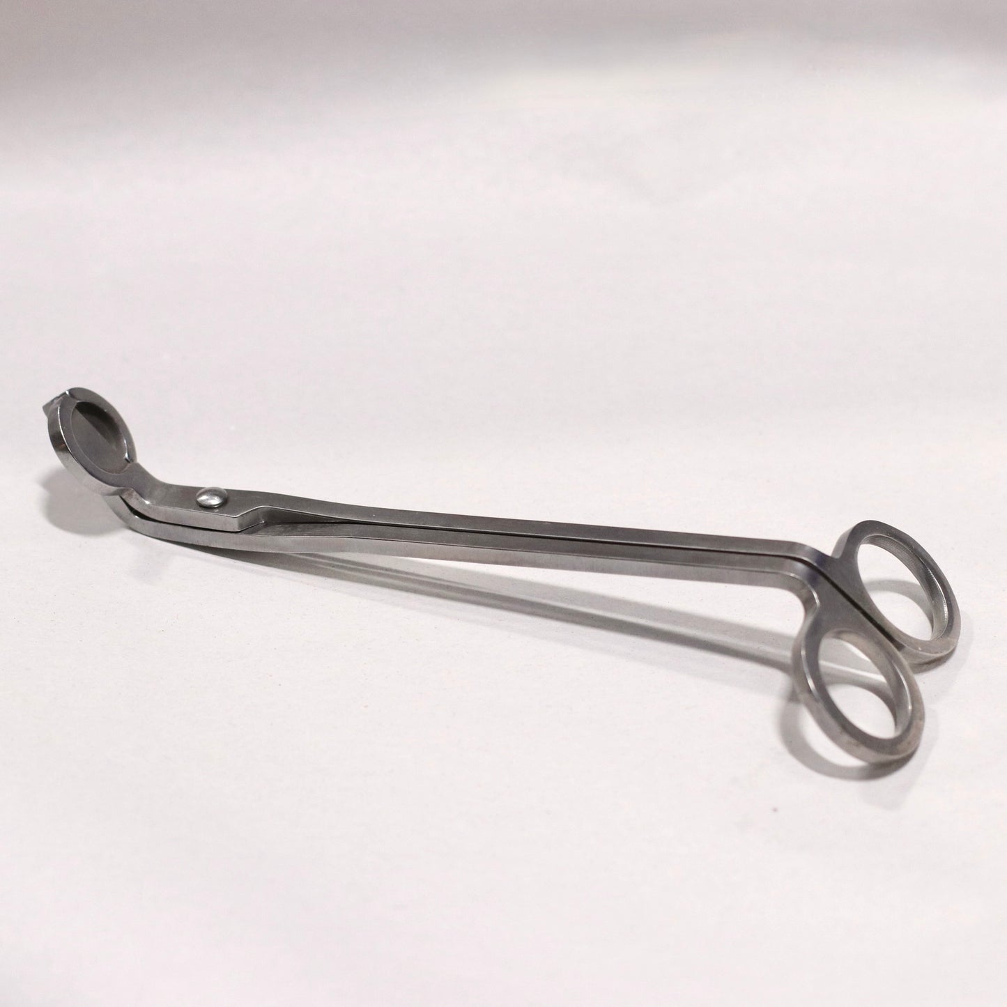 A metal wick trimmer on a white background.