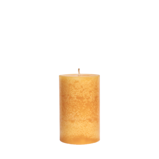 A single handcrafted pillar candle featuring a mottled wax finish with a distinct snowflake-like pattern in a solid apricot yellow hue.