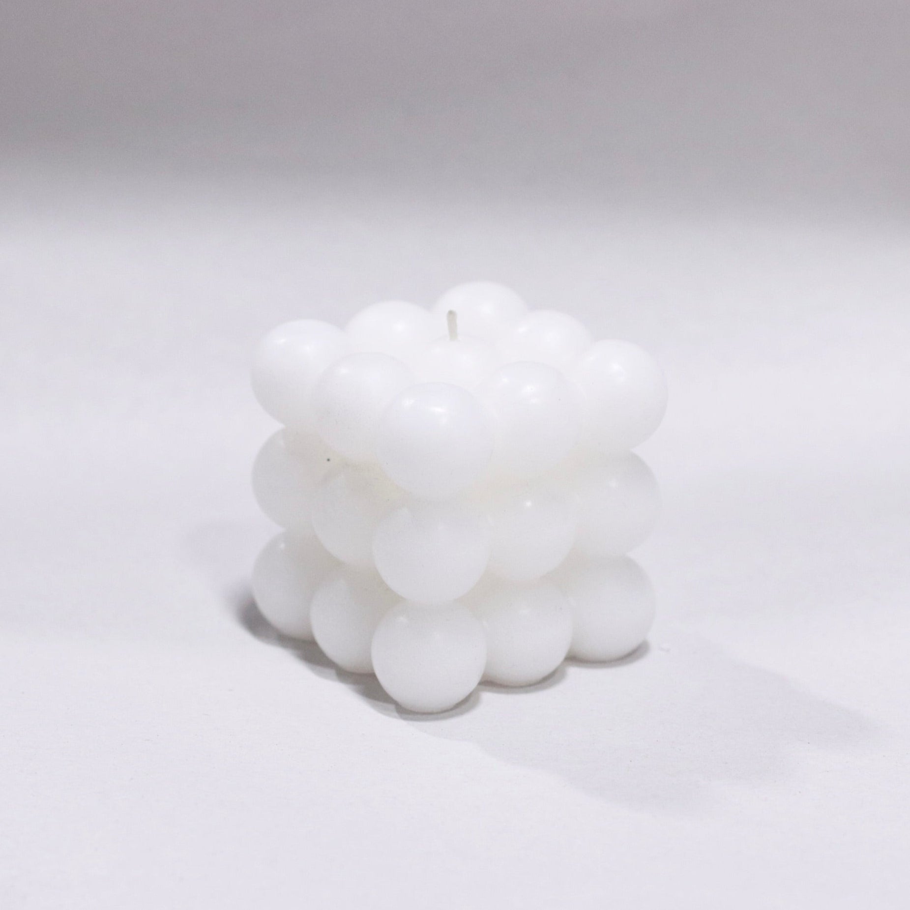 White bubble pillar candle on a light gray background.