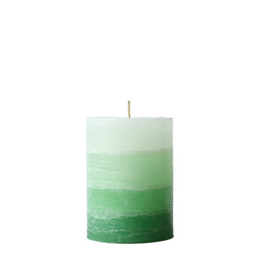 A solid-color gradation pillar candle with four distinct layers of green, featuring a textured, weathered surface for a Nordic-inspired look.
