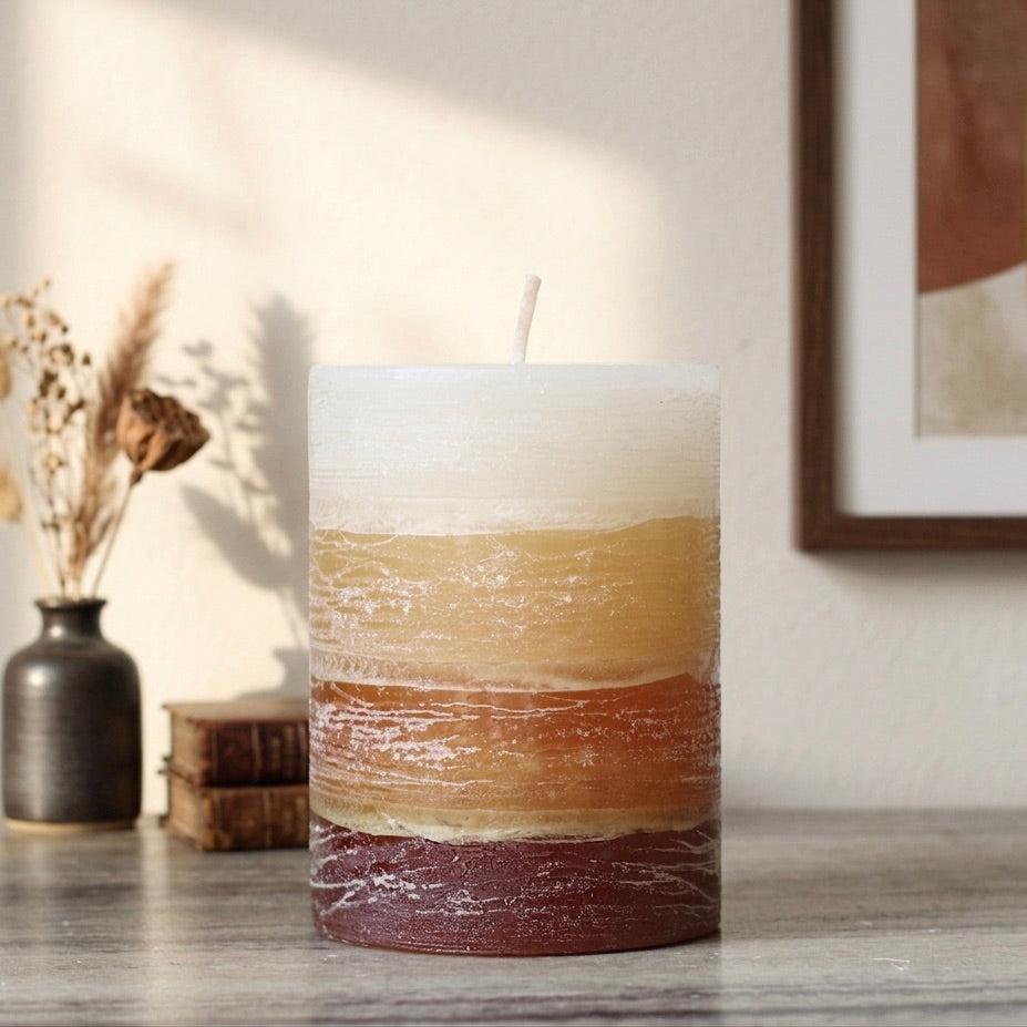 Gradation brown cylindrical candle on a wooden surface with a neutral background