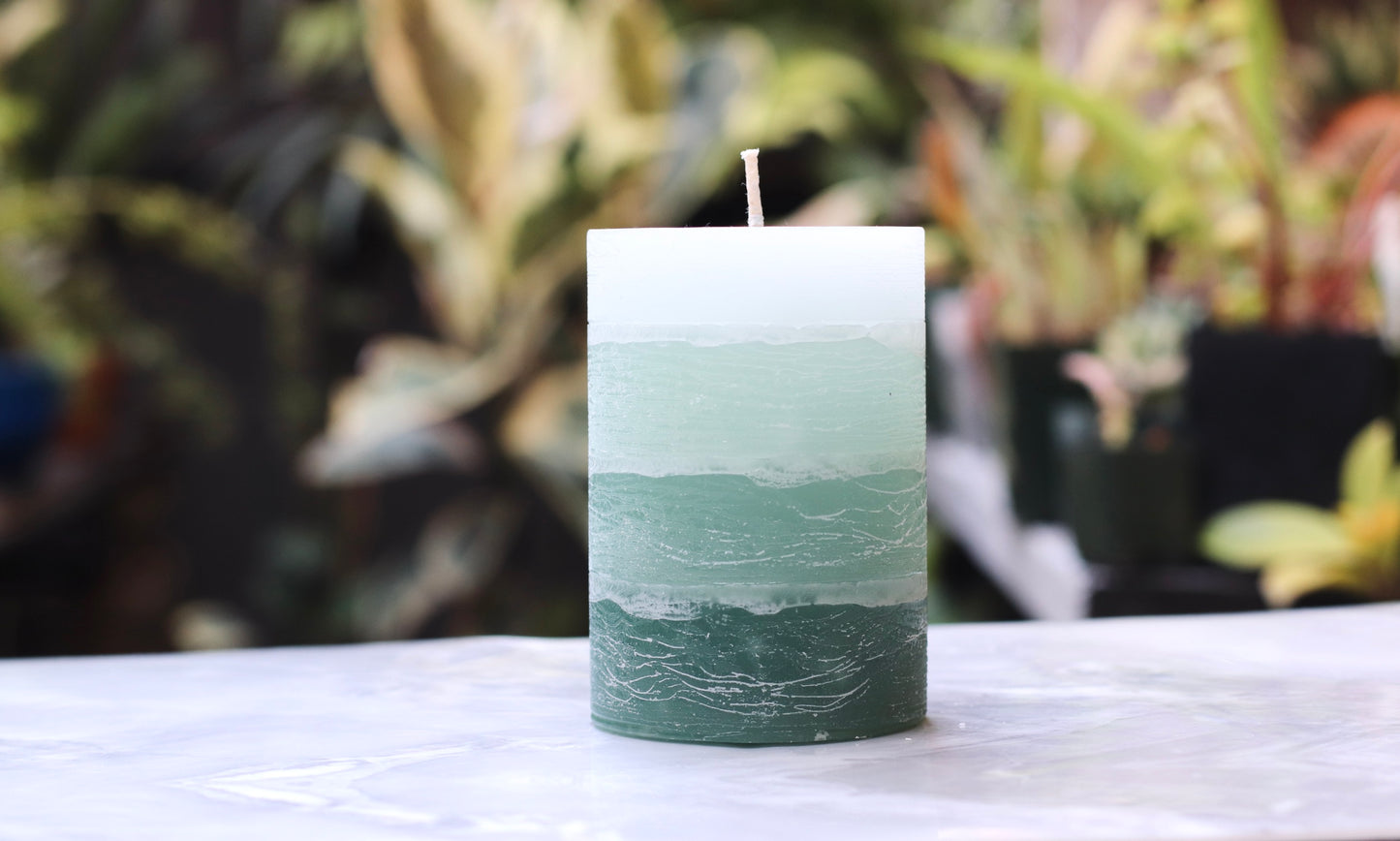 Sage Green on a white surface with a blurred plant background