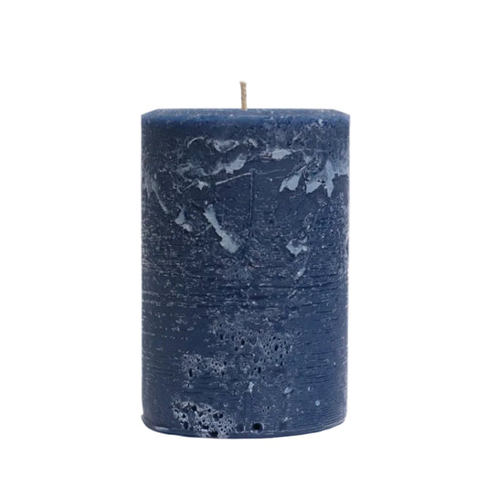A single dark blue cylindrical candle with a textured, marbled surface and a single wick, standing upright on a white surface against a white background.