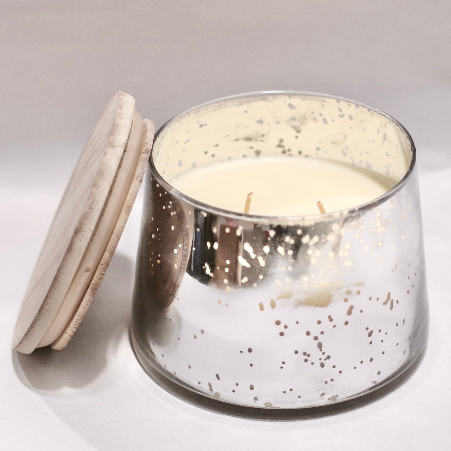 Candle in a glass jar with a decorative lid on a light gray background. The scent is paper white. The net weight of the candle is 14.8oz. This candle comes with two wicks. Burn time is around 55 hours. 
