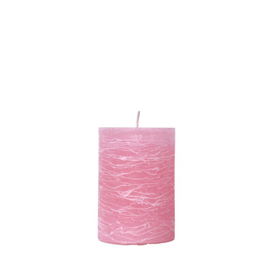 A minimalist Nordic-style pillar candle in a solid pink, featuring horizontal textured lines and a handcrafted rustic finish.