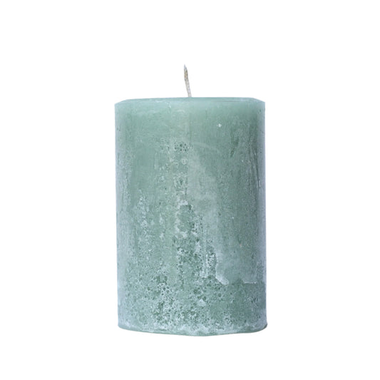 A handcrafted sage green pillar candle with a 'Petrified' rustic texture, showing a weathered, frosted, stone-like finish in muted herb tones. 