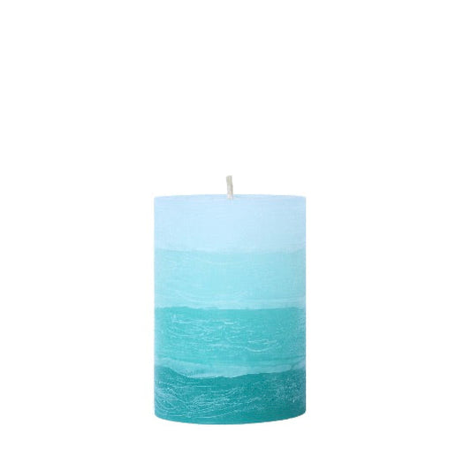 A solid-color gradation pillar candle with four distinct layers of turquoise, featuring a textured, weathered surface for a Nordic-inspired look.