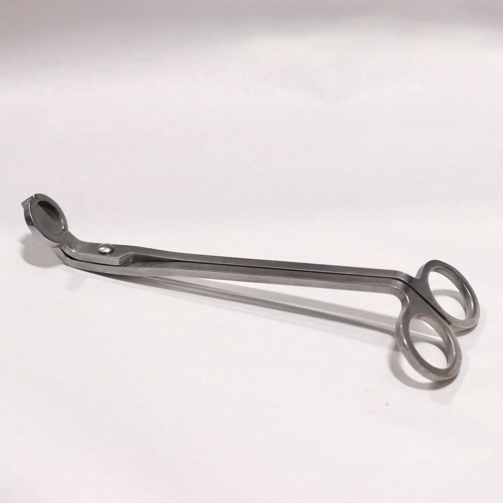 A metal wick trimmer on a white background.